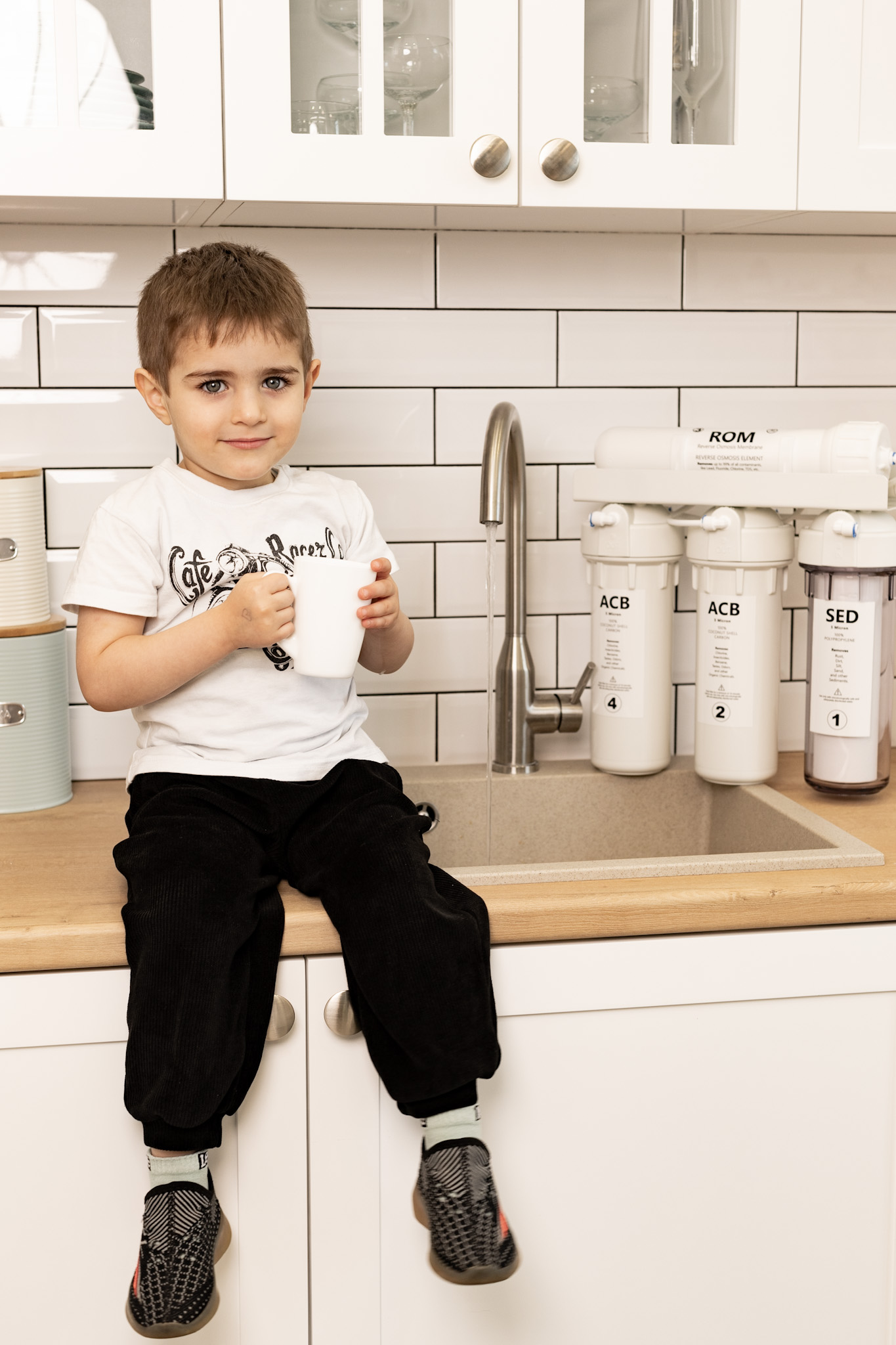 A child holding a cup in a kitchen with a Filac system